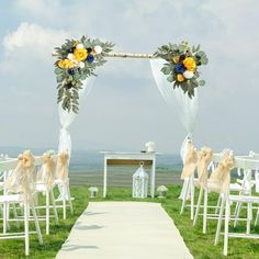 an outdoor ceremony set up with white chairs and yellow flowers