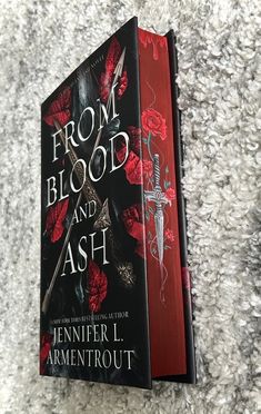 the book from blood and ash by jennifer l armentrouut is laying on carpet