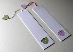 two bookmarks with hearts on them are next to a string that is hanging from the wall