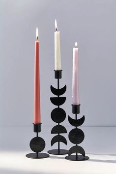 three candles are placed next to each other in different shapes and sizes, with one candle lit