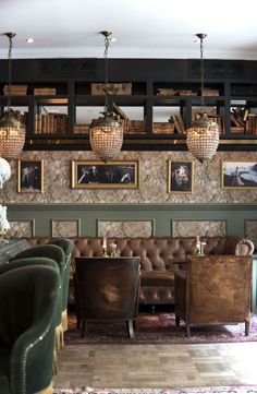 a room with couches, chairs and pictures on the wall above them in an old fashion restaurant