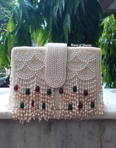 This is a beautiful handcrafted clutch bag made with love.It has intricate handwork which showcases the Indian craftsmanship by our local artisans. It comes with a pearl handle. Details  - Single side handwork  - Fabric lining on the inside to keep your belongings safe  - Magnetic lock closure  - Detachable handle  This clutch can be worn as a crossbody bag or a shoulder bag with the sling chain or can simply be carried in hand.It is spacious enough to carry mobile phones, lipsticks, Keys and ot Pearl Handle Clutch As Gift, Luxury Pouch Flap Bag With Detachable Handle, Luxury Shoulder Bag With Pearl Handle As A Gift, Luxury White Flap Bag As A Gift, Elegant Party Potli Bag With Openable Design, Elegant Openable Potli Bag For Parties, Elegant Festive Openable Potli Bag, White Clutch For Festivals Gift, White Clutch For Festivals