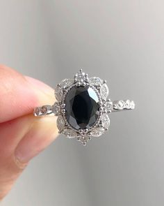 a person holding an engagement ring with a black diamond in it's middle finger