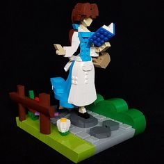 a lego model of a woman holding a book