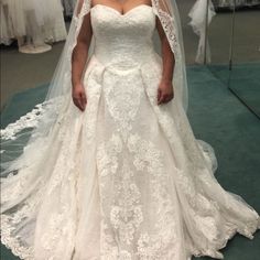 a woman wearing a wedding dress and veil standing in front of some dresses on display