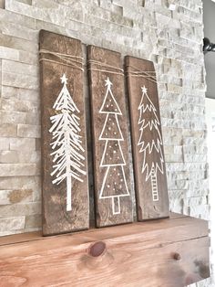 three christmas trees painted on wooden planks in front of a brick fireplace mantel