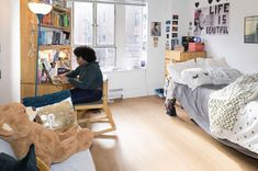 a person sitting on a bed in a room with lots of furniture and pictures on the walls