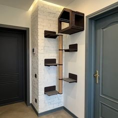 a cat tree in the corner of a room with white brick wall and blue door