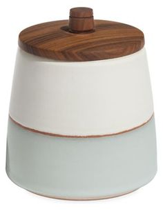 a white and brown ceramic jar with wooden lid