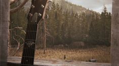 an acoustic guitar sitting on top of a wooden table in front of a mountain view