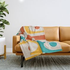 a couch with a blanket on it next to a potted plant