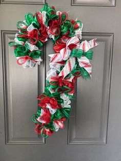 a christmas wreath is hanging on the front door with ribbons and bows attached to it