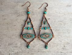 a pair of earrings with turquoise beads and copper wire hanging from the earwires