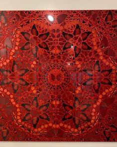 a painting with red and black designs on the bottom, surrounded by smaller circles that appear to be crocheted