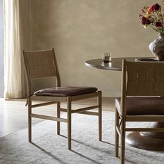 a table with two chairs and a vase on top of it next to a window