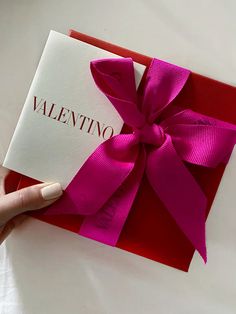 a hand holding a valentine's day card with a pink bow