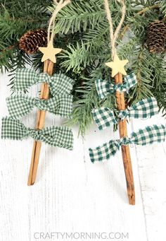 two wooden stick ornaments with green gingham bows and pine cones hanging from them