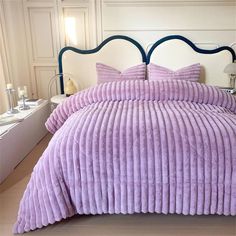 a bed with purple bedspread and pillows on it