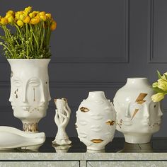 three white vases with yellow flowers in them