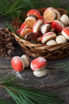 a basket filled with red and white cookies next to pine cones on top of a wooden table