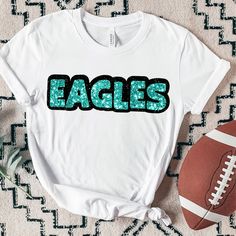 an eagles shirt sitting on top of a rug next to a football and a ball