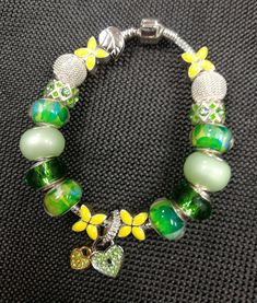 Bright green and yellow remind me of yellow daffodils and green grass, so pretty! This silver snake link large bead bracelet has those bright yellow and green beads, made of mixed green beads, yellow petals, light mint and silver basket beads. A green and gold heart dangle makes it a winner! So fun and pretty for any occasion! A beautiful silver leaf clip bead holds your beads on the bracelet while you are putting it on. Warning!  Please be aware these beads could choke a child if they came off Cheap Green Novelty Bracelets, Large Bead Bracelet, Silver Basket, Yellow Petals, Gray Bracelet, Yellow Daffodils, Green Beads, Memory Wire Bracelets, Seed Bead Bracelets