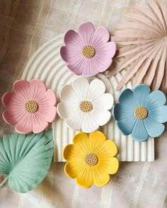 colorful paper flowers are arranged on a white plate