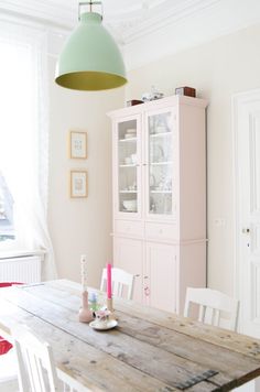 a dining room table with white chairs and a green light hanging over it's head