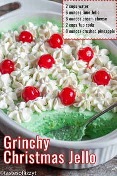 a green and white cake with cherries on top is in a pan that says grinchy christmas jello