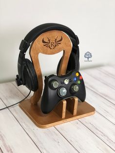 a game controller and headphones stand on a wooden stand with a white wall behind it