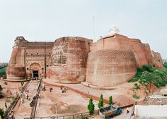 an aerial view of a large brick building in the middle of a town with people walking around it