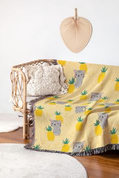 a couch covered with a yellow pineapple and koala print blanket next to a white rug