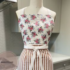 an apron on display in a kitchen with a flowered top and striped skirt underneath it