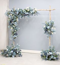 a wedding arch decorated with blue flowers and greenery