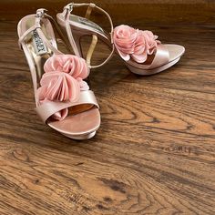 a pair of pink high heeled shoes with flowers on the toes and heels are sitting on a wooden floor