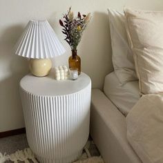 a white table sitting next to a couch in a living room with pillows on top of it