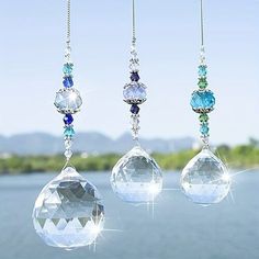 three crystal necklaces hanging from strings next to water