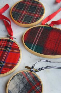 three red and black tartan plaid ornaments hanging from wooden hoops on a marble surface