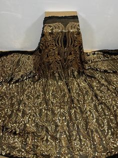 a gold and black dress sitting on top of a wooden floor next to a white wall