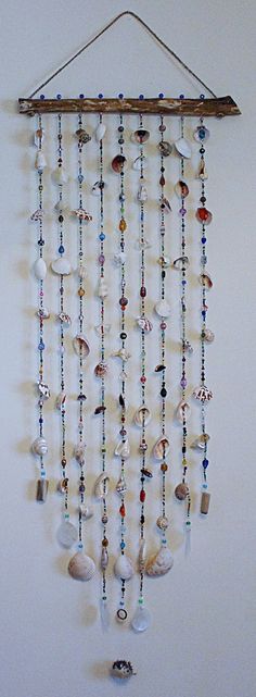 a wind chime with shells and beads hanging from it's side on a wall