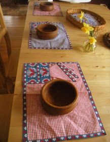 a wooden table with place mats and bowls on it