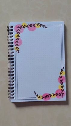 a spiral notebook with flowers and leaves on the cover is sitting on top of a table