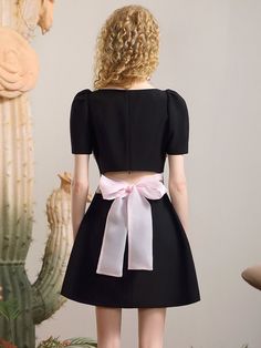 the back of a woman's dress with a pink bow at the waist and short sleeves