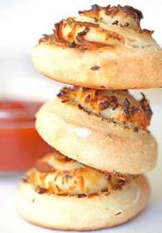 three bagels stacked on top of each other with cheese and sauce in the background