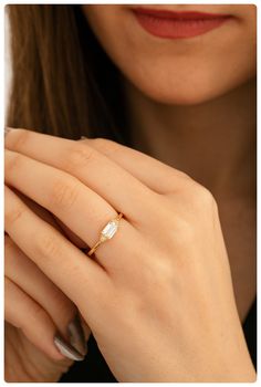 a close up of a person wearing a gold ring with a white diamond on it