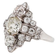 This show stopping antique ring hails from the 1920s and exudes all the art deco elegance of the era. Rendered in pure platinum, brilliant white diamonds make an architectural design around a 1.65ct old-mine-cut stone. Designed to make a statement then and now, this bold ring is one-of-a-kind. Appraisal available upon request. Stones: Center: 1.65ct White Old Mine Cut Diamond (Color O-P, SI-1), Top/Bottom stones: Two White Brilliant Cut Diamonds (Total .81tcw, Color I-J, Clarity VS1-SI1), Sides: Art Deco Platinum Diamond Ring In Diamond White, Art Deco Platinum Diamond Ring With Single Cut Diamonds, Antique White Diamond Ring In Platinum, Antique White Diamond Platinum Ring, Art Deco Platinum Diamond Ring With Rose Cut Diamonds, Antique White Platinum Diamond Ring, Art Deco Platinum Ring With Rose Cut Diamonds, Art Deco Platinum Rings With Rose Cut Diamonds, White Platinum Diamond Ring In Art Deco Style