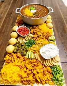 a platter filled with chips, dips and other foods on a wooden table