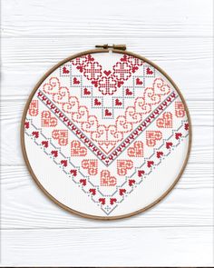 a cross stitch heart on a white wooden background