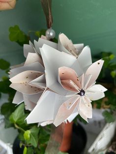 an origami flower hanging from a plant