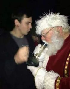 a man dressed as santa claus is talking to a young boy with a pipe in his mouth